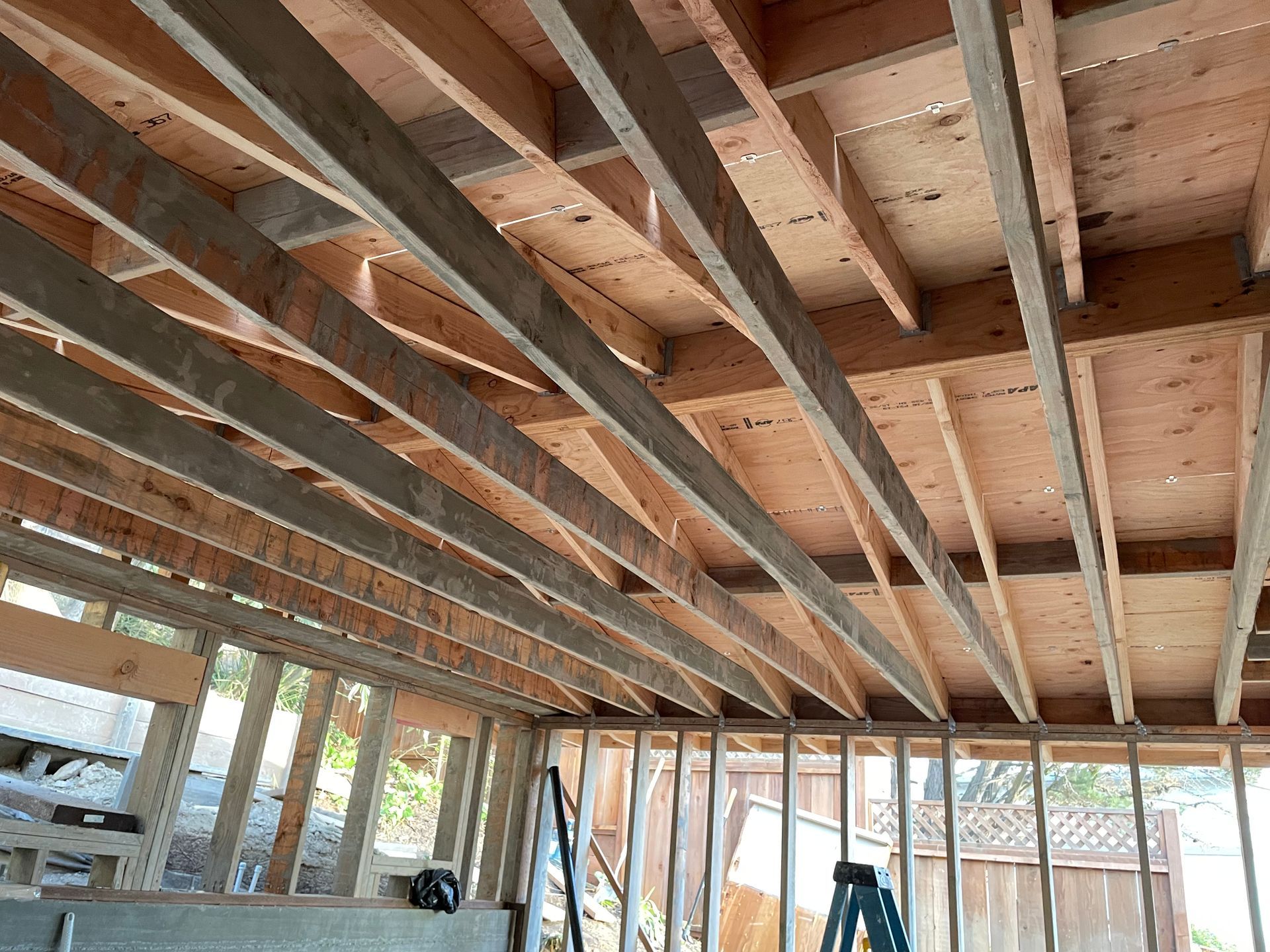 Exposed wooden ceiling joists and roof framing in an unfinished room under construction