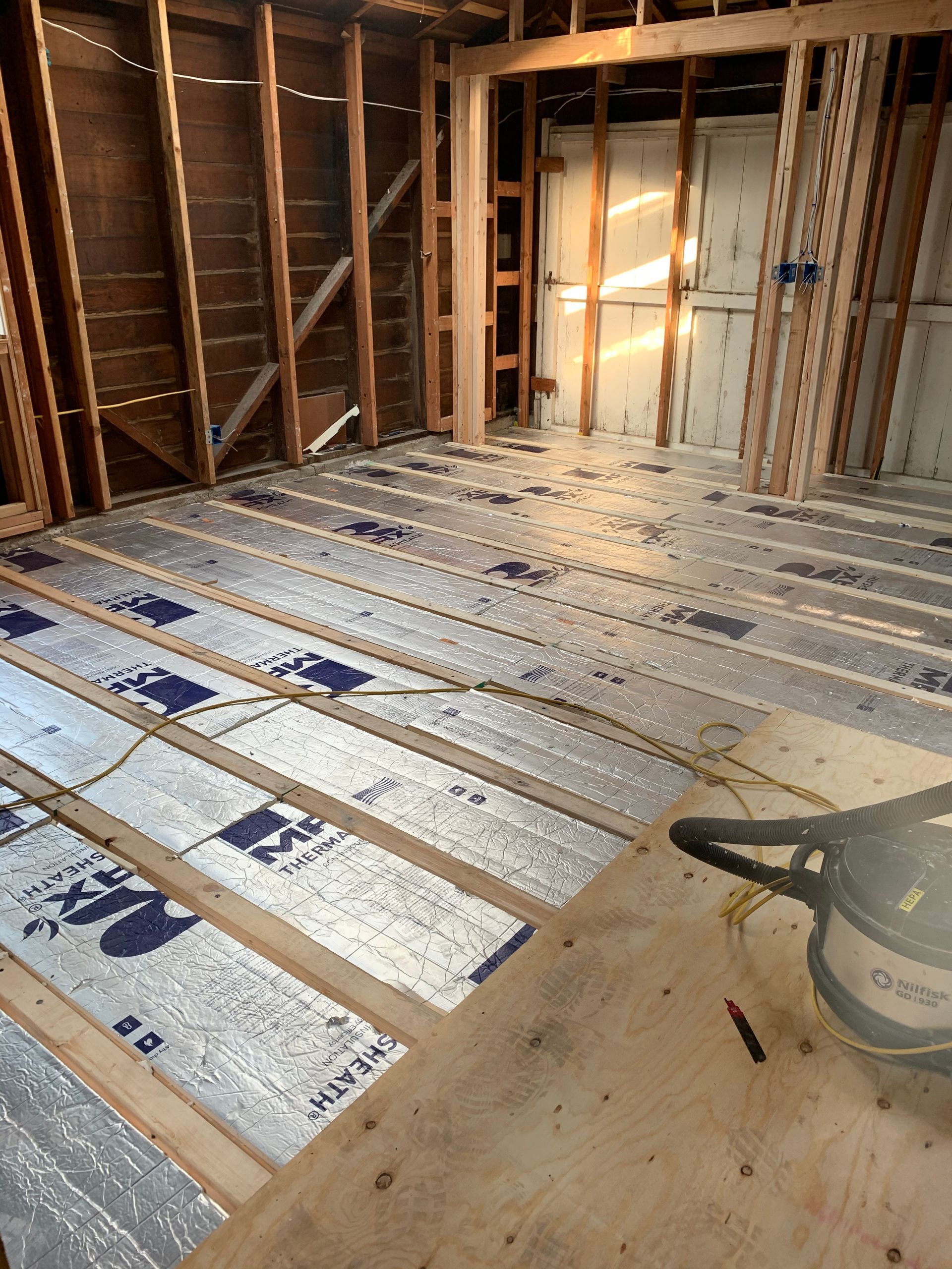 Partially insulated house interior with exposed framing and subfloor under construction