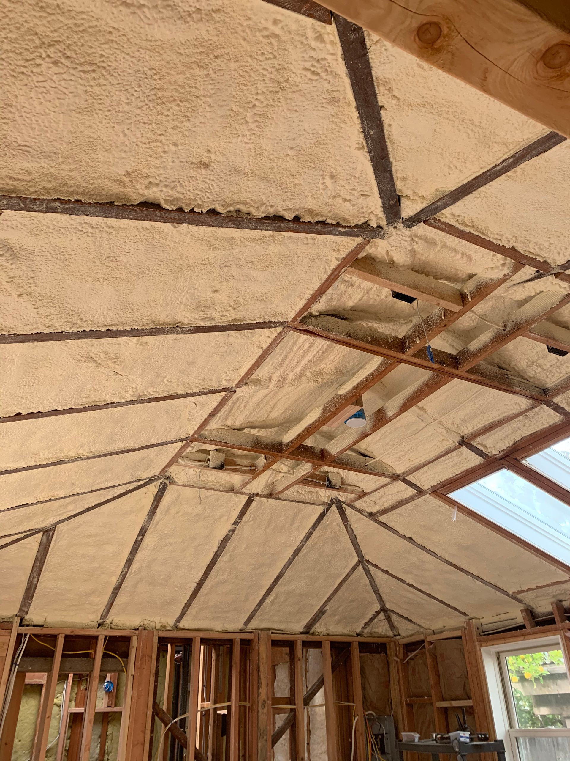 Interior roof framing with spray foam insulation and skylight openings in an unfinished house