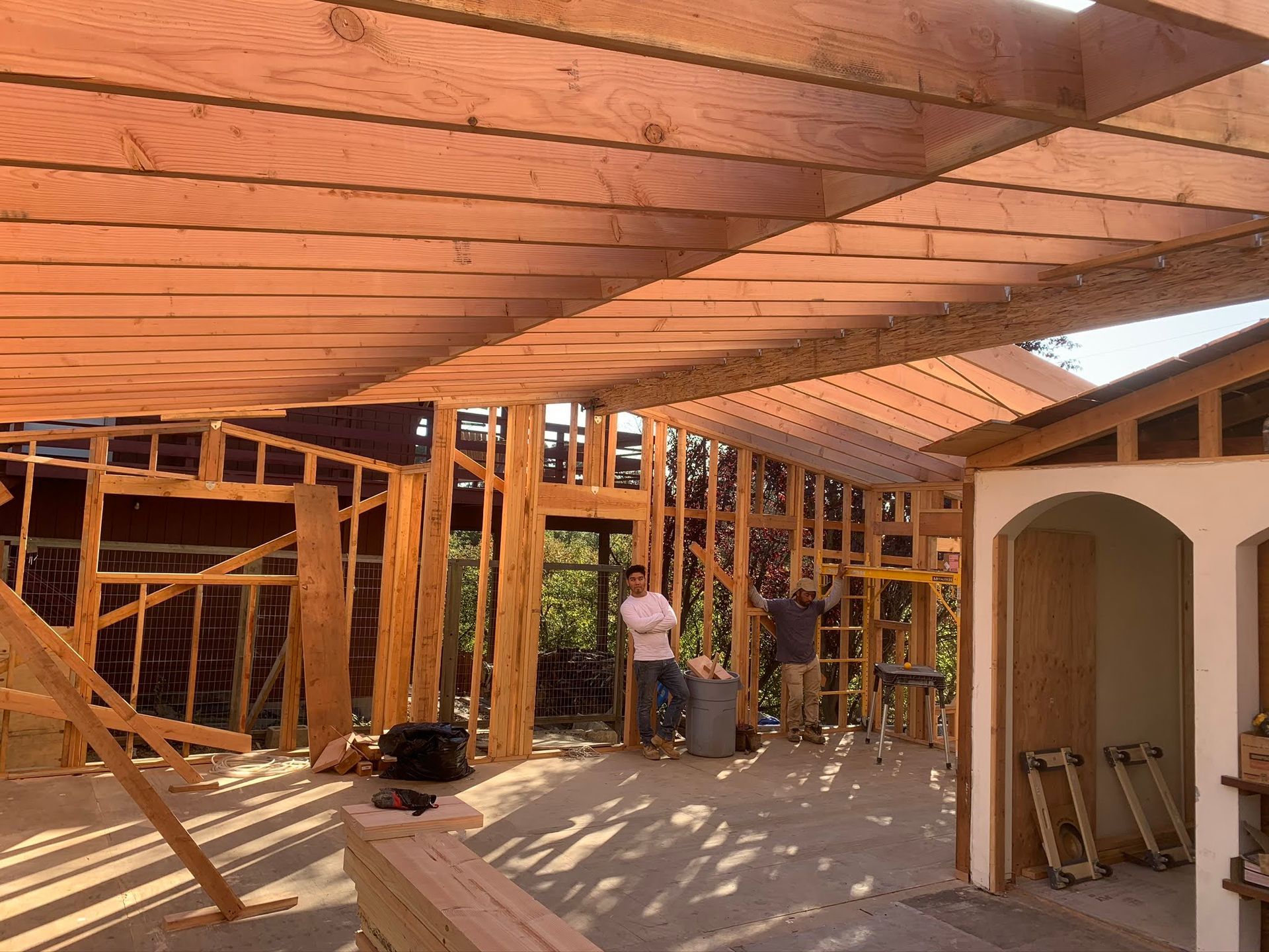 Partially built house interior with exposed wooden framing and a worker under construction.