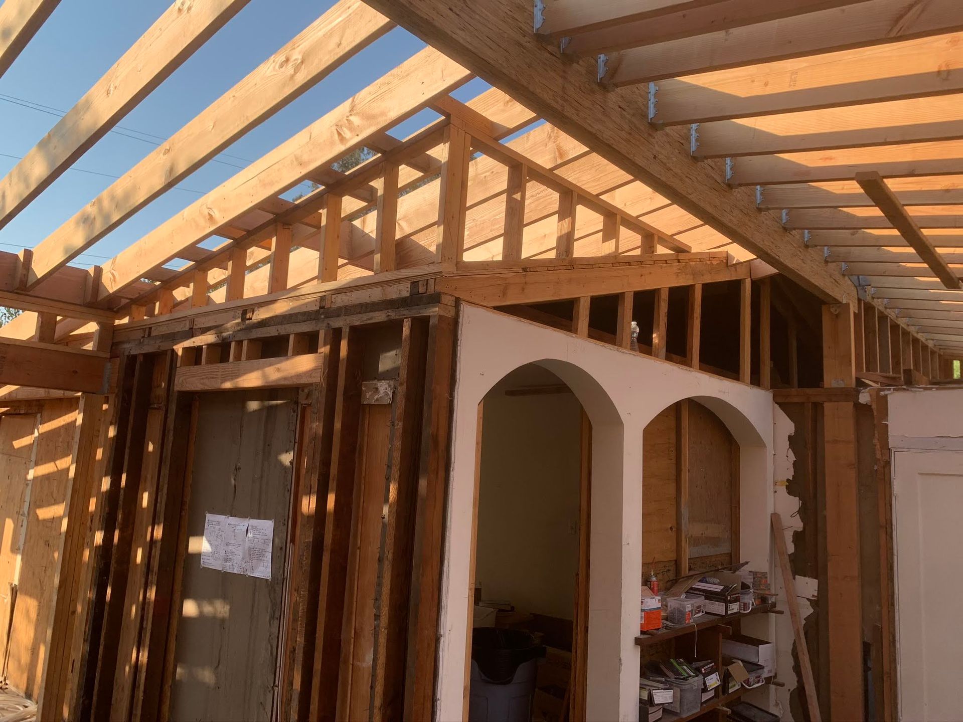 Partially built house interior with exposed wooden roof beams and an unfinished archway wall