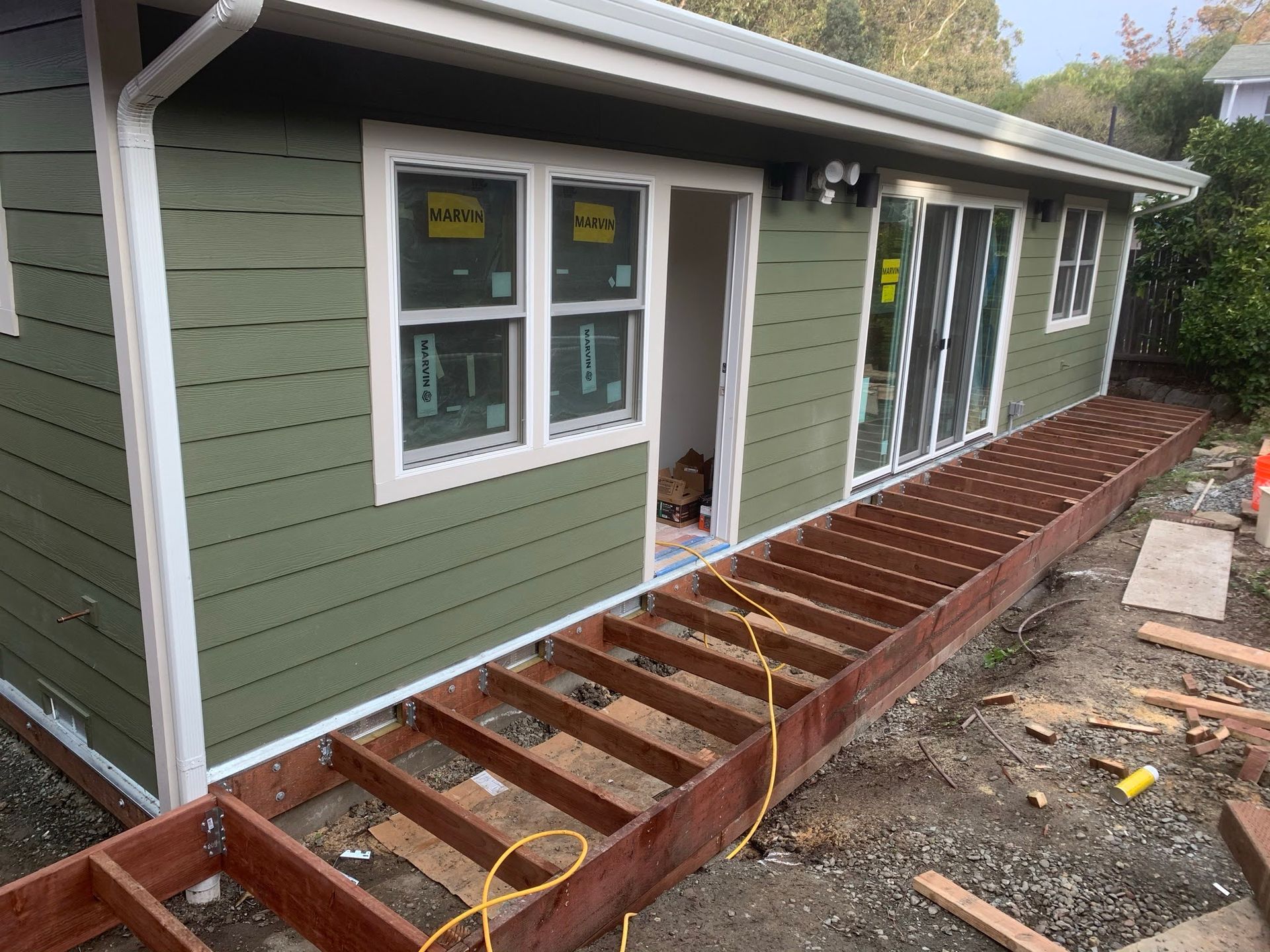 House exterior with green siding and a partially built wooden deck under construction