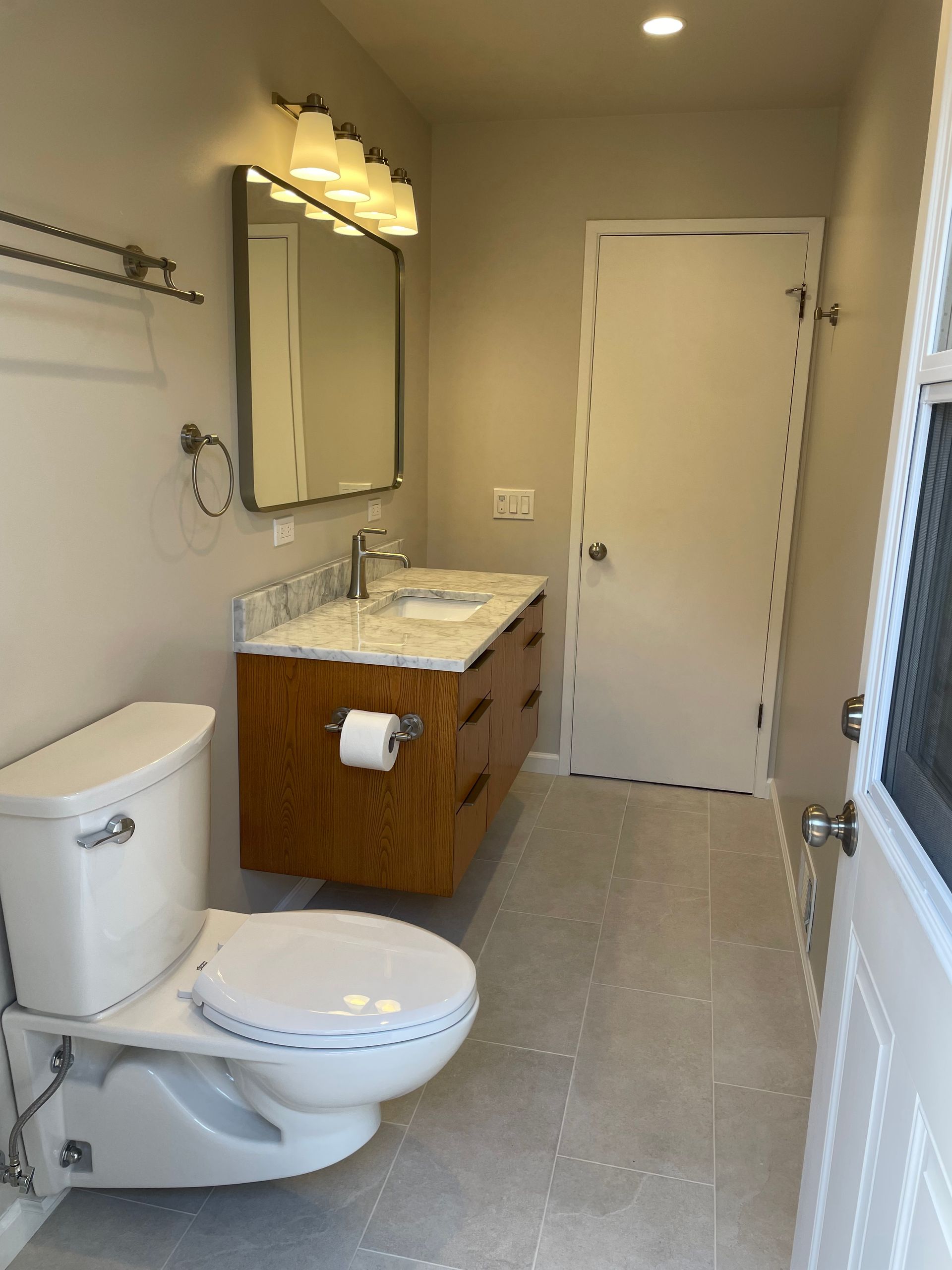Small bathroom with toilet, vanity, mirror, and shower curtain in beige tones.
