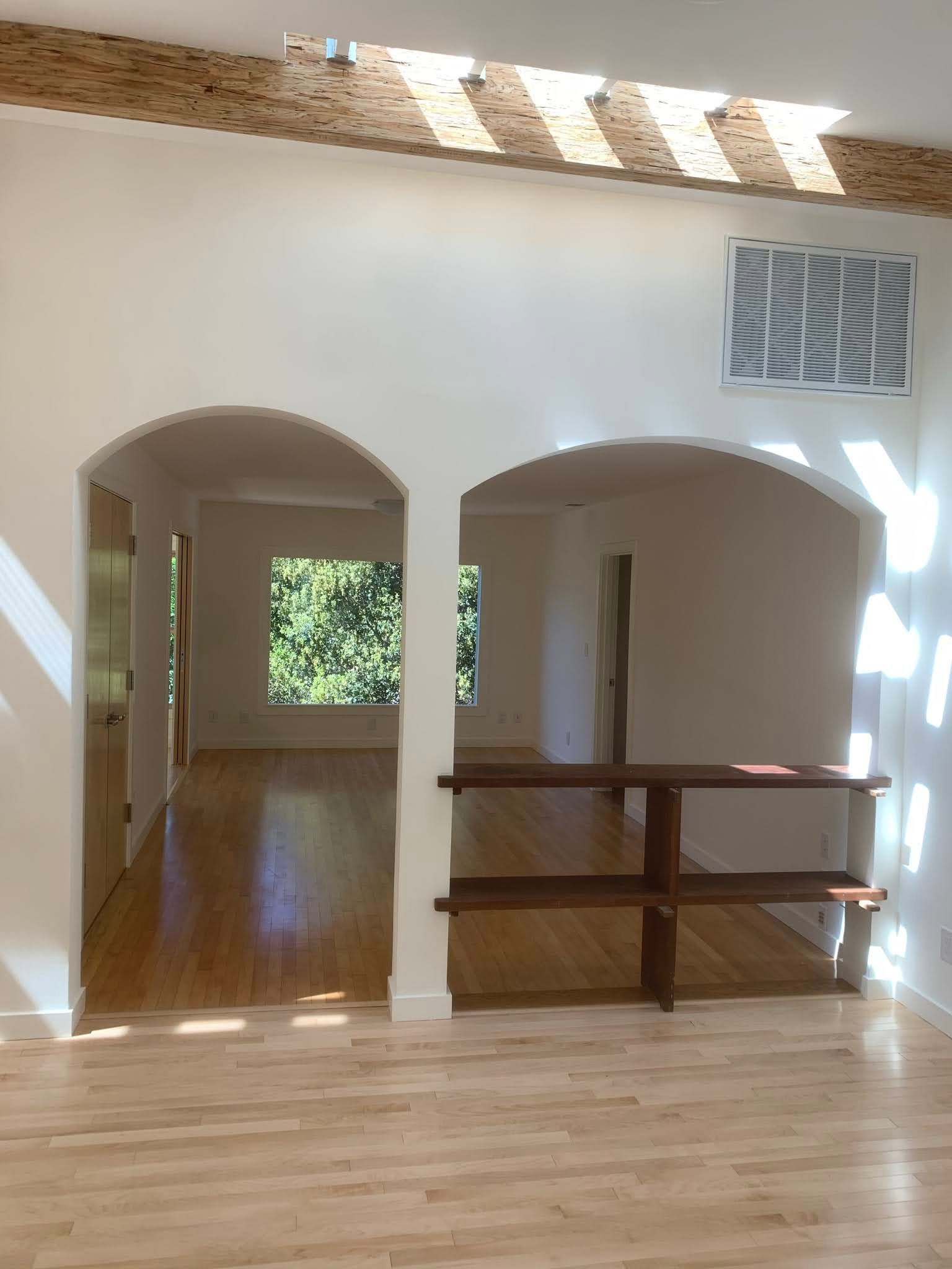 Bright loft with arched openings, wood floors, skylight, and a half-wall railing overlooking a lower level