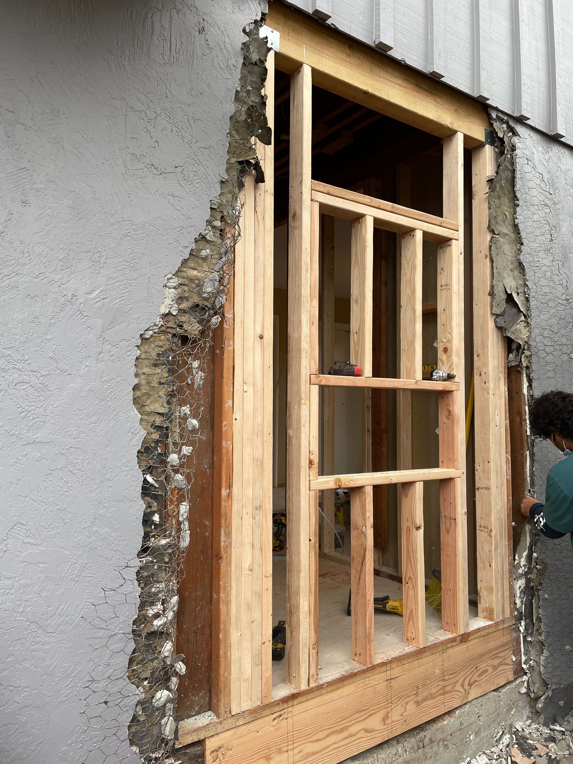 Partially framed doorway in a gray wall with exposed wood and plaster during construction