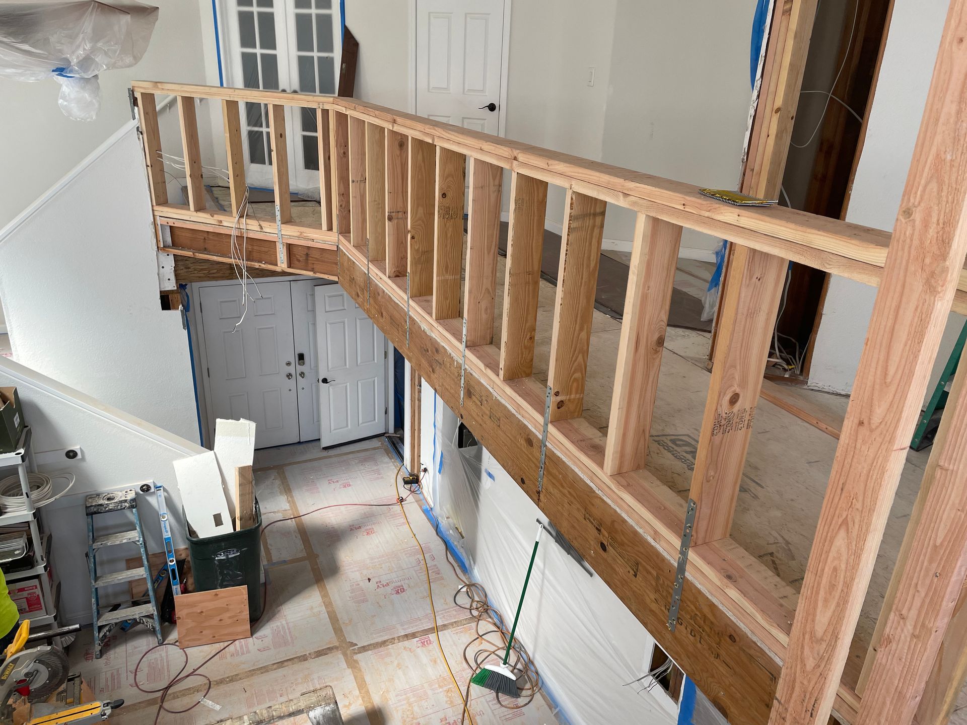 Wooden railing framing an unfinished interior balcony or loft above a staircase area