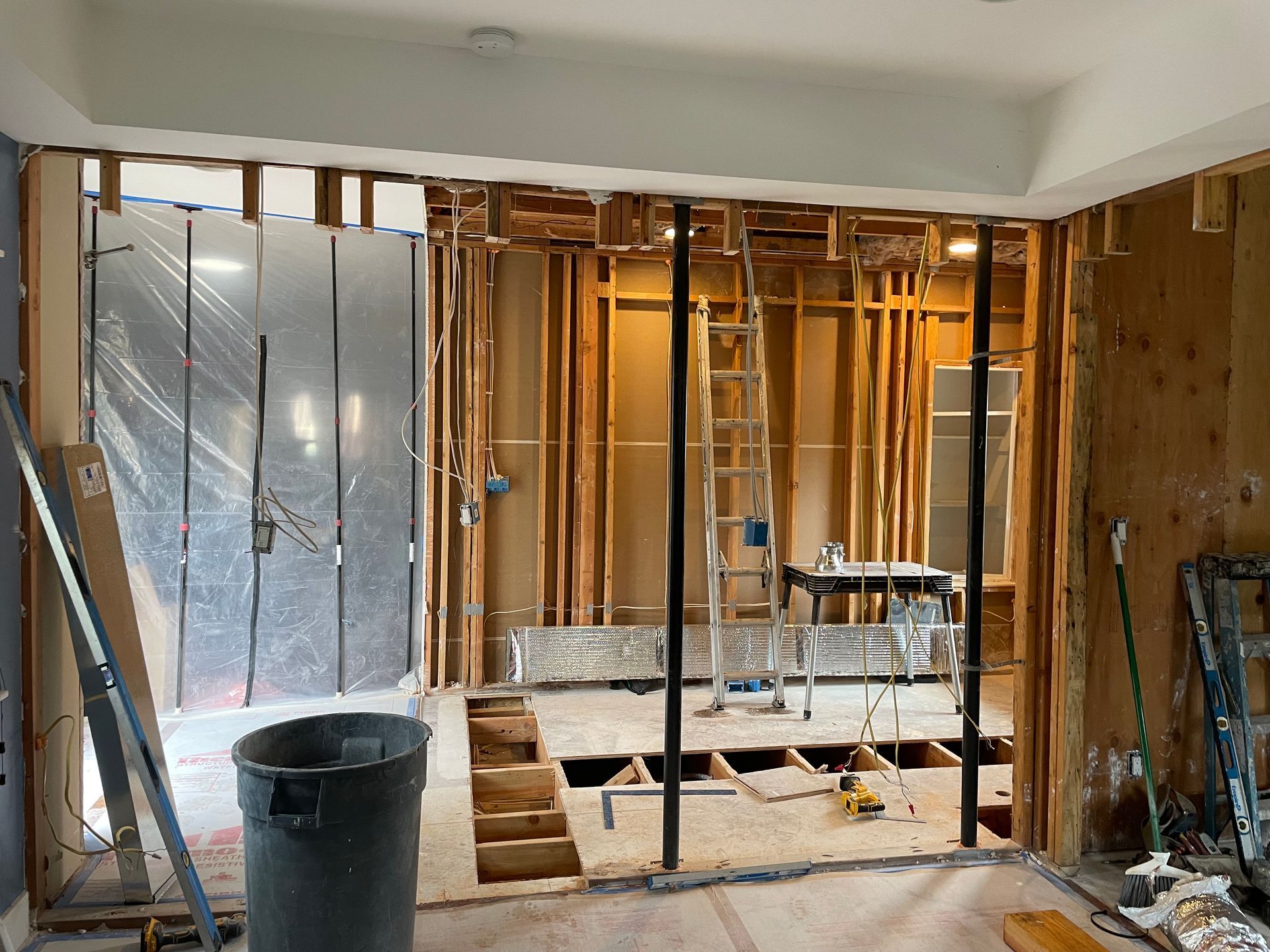 Renovated room with exposed studs, tools, and a partially removed wall in progress
