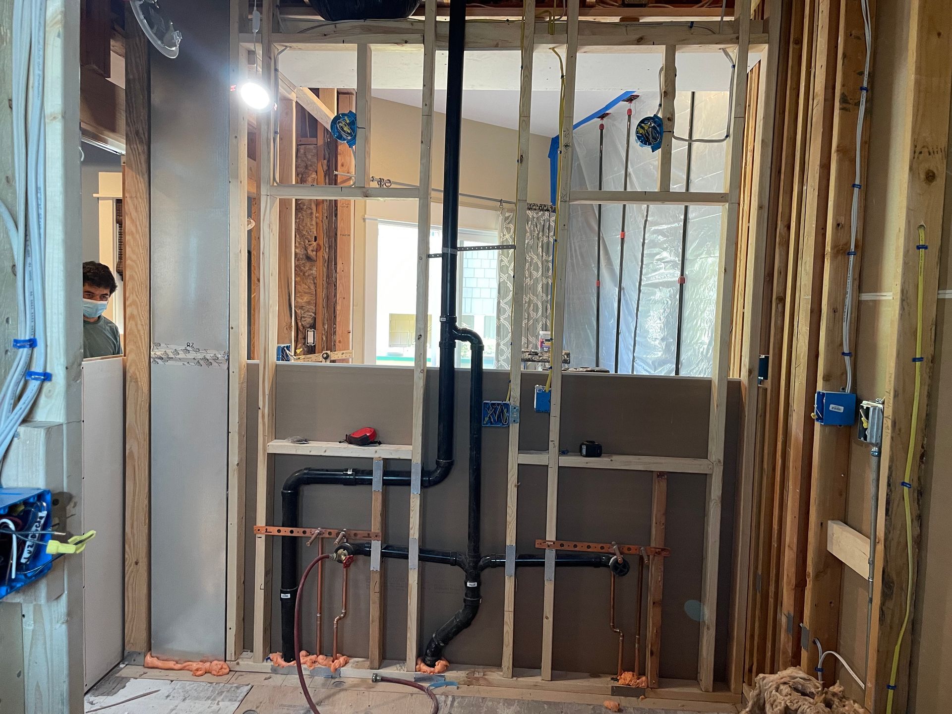 Framed interior wall with exposed plumbing and electrical work during renovation
