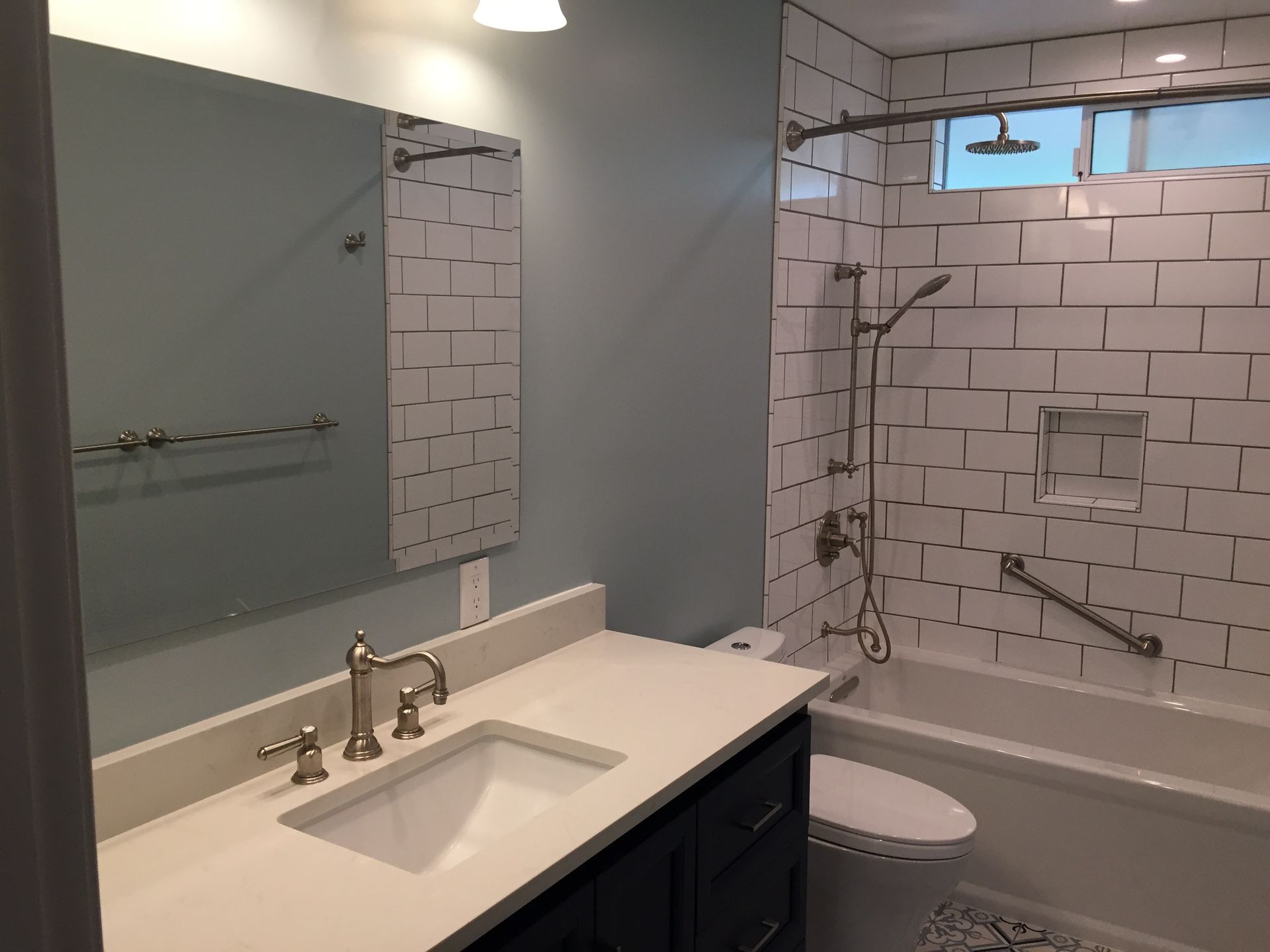 Accessible bathroom with white vanity, large mirror, and tiled shower beside a toilet