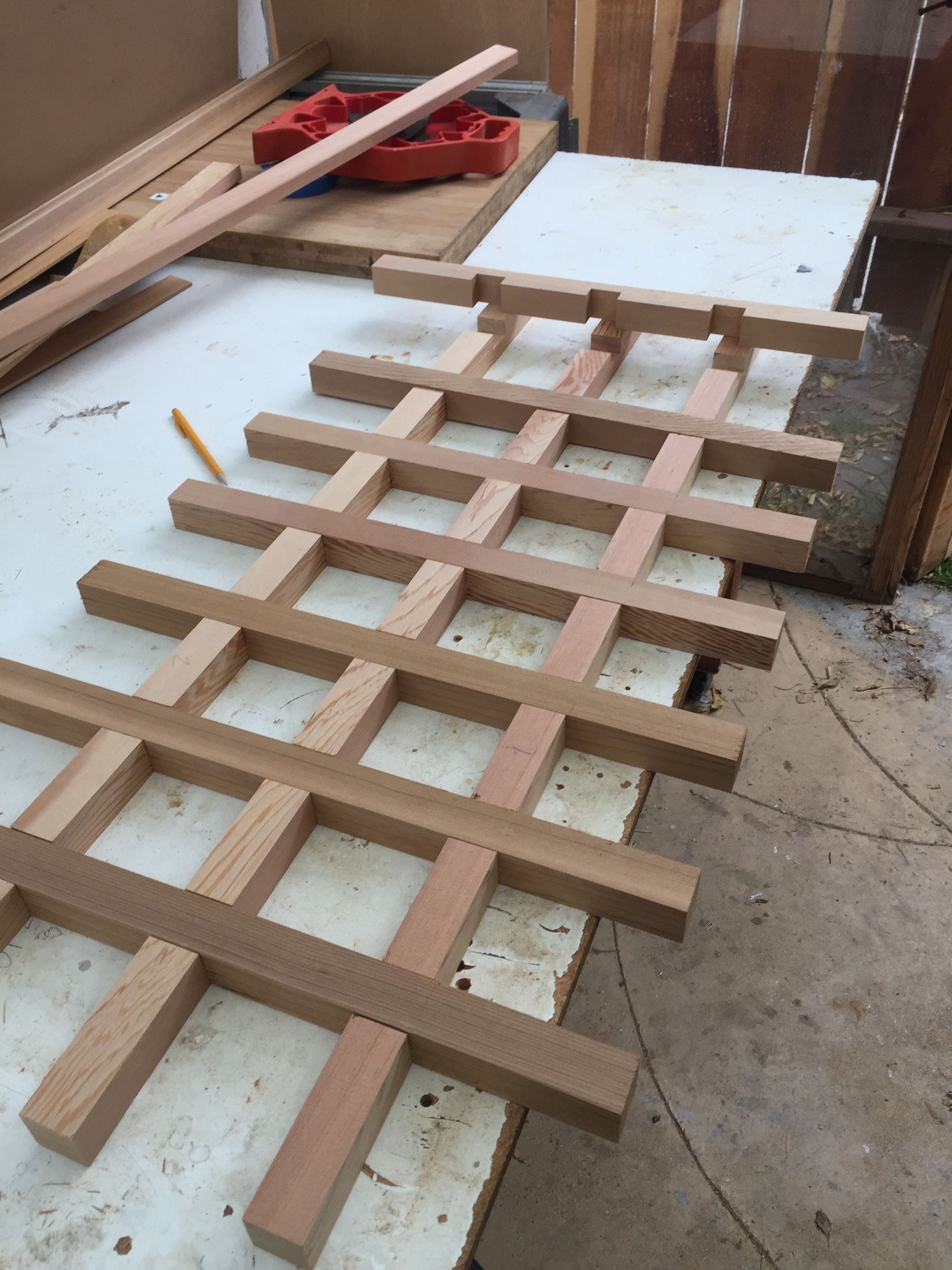 Wooden lattice frame assembled on a workbench in a workshop, with tools and lumber nearby