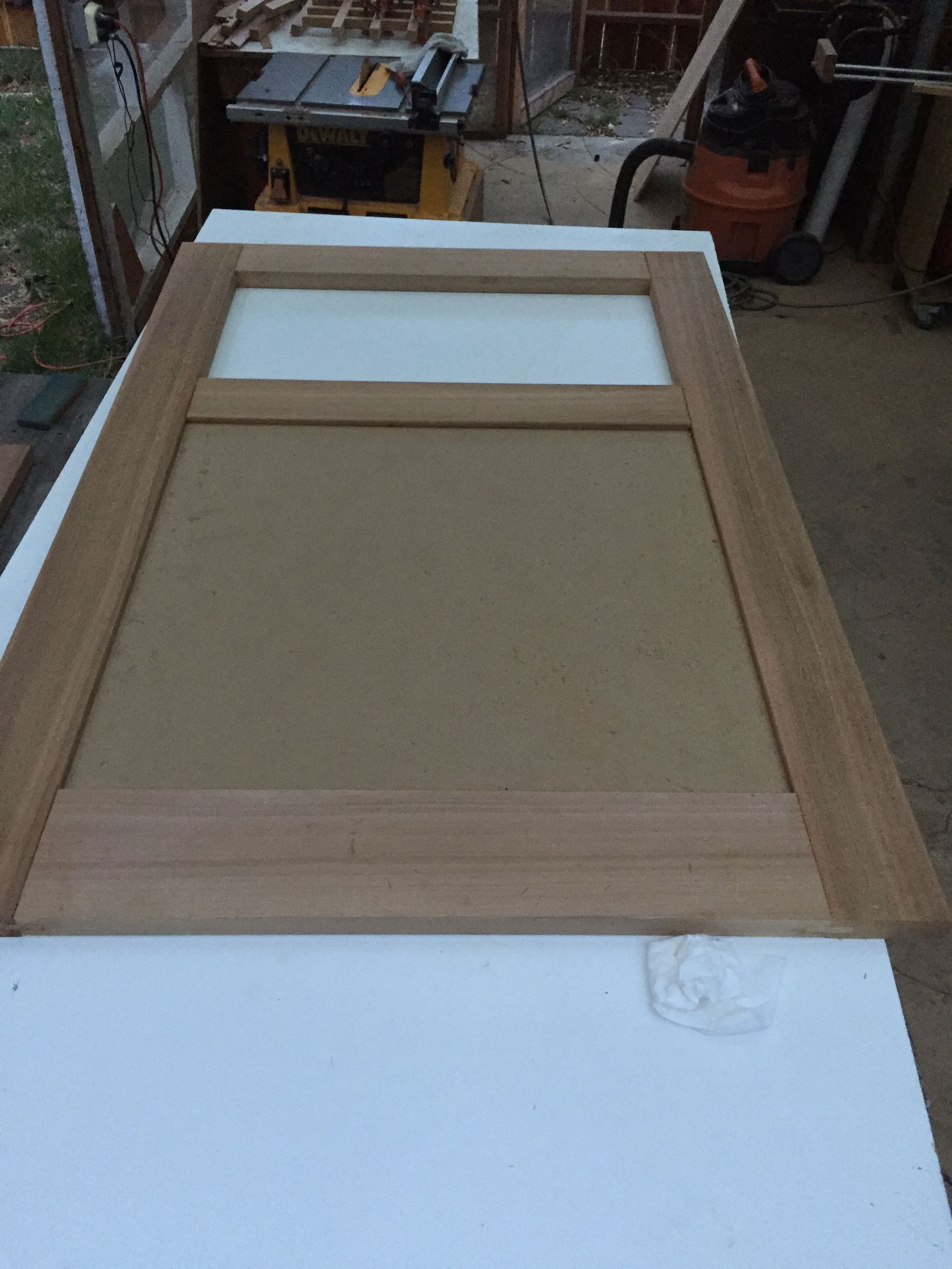 Wooden framed screen door or panel leaning on a workbench in a workshop.