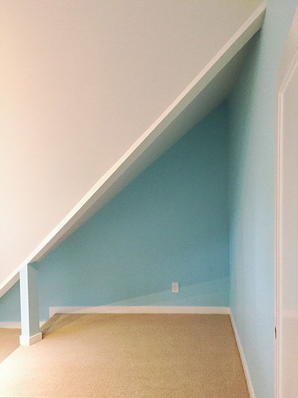 An empty room with a slanted ceiling and blue walls.