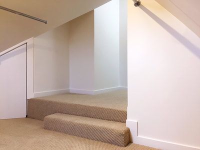 A staircase with carpeted steps leading up to a white wall.