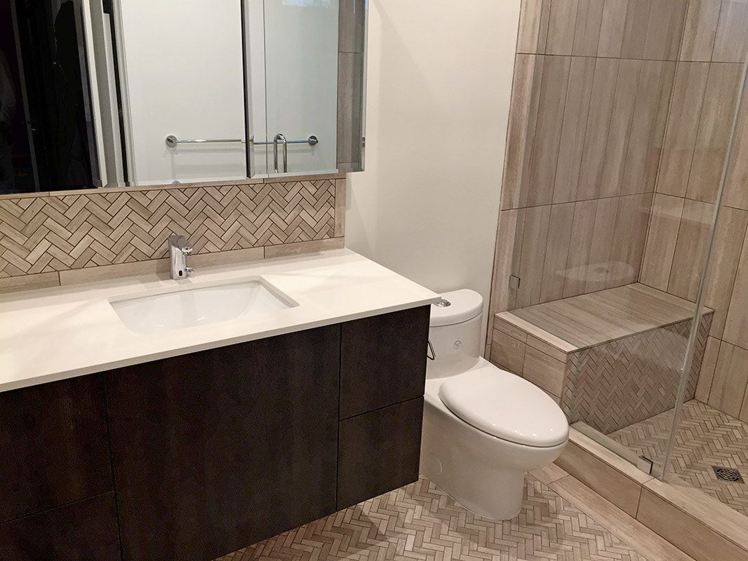 A bathroom with a toilet , sink , mirror and walk in shower.