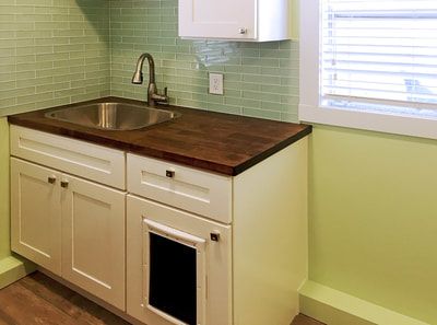 A kitchen with a sink , cabinets , and a window.