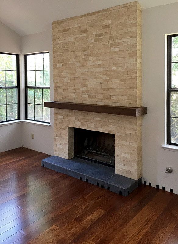 A living room with a fireplace and two windows.