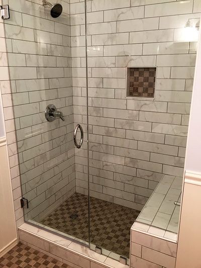 A bathroom with a walk in shower with a glass door.