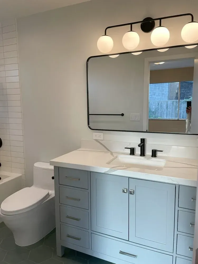 Modern bathroom vanity with mirror, white countertop, black fixtures, and wall sconces
