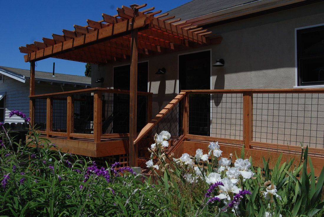 A house with a wooden deck and flowers in front of it