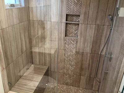 A walk in shower with a bench and a glass door.
