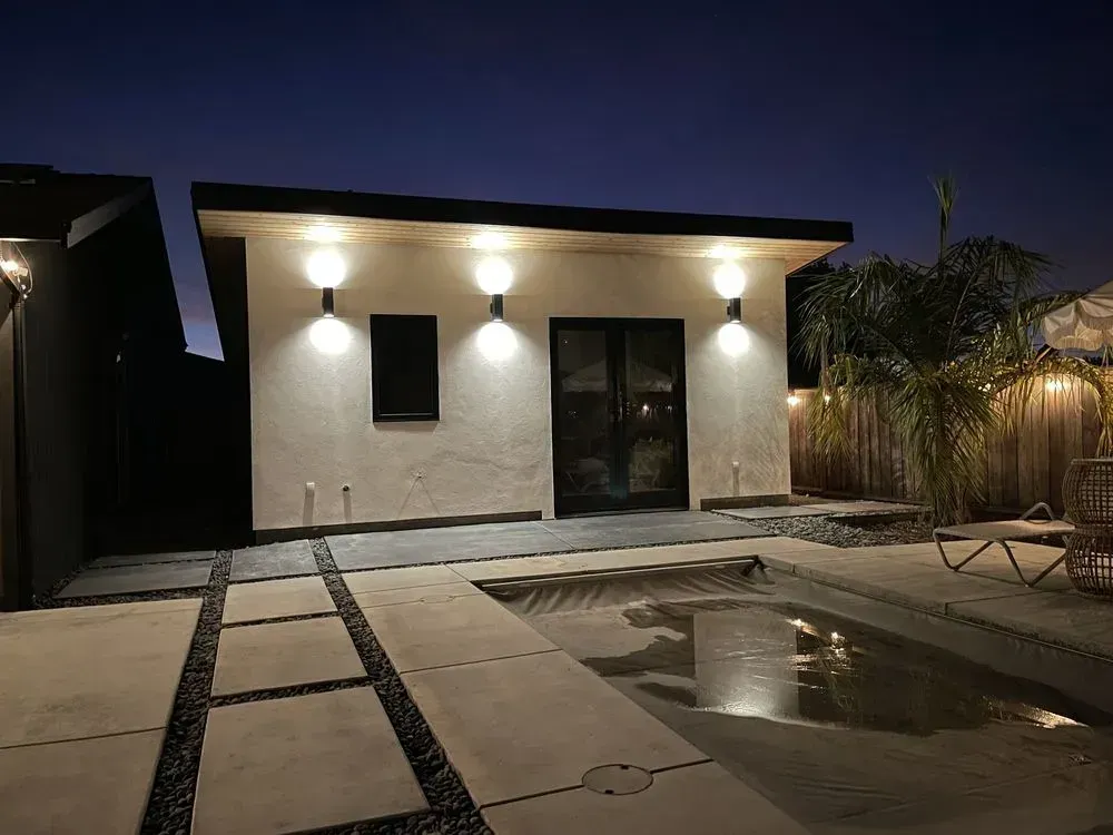 Multi-zone outdoor living space in Richmond with lighting, paver walkway, and water feature at dusk