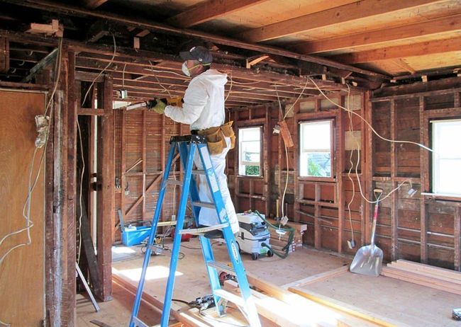 A man is standing on a ladder in a room.