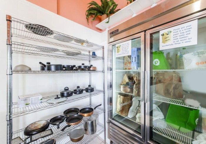 Commercial kitchen storage shelves beside a glass-door refrigerator in a bright room