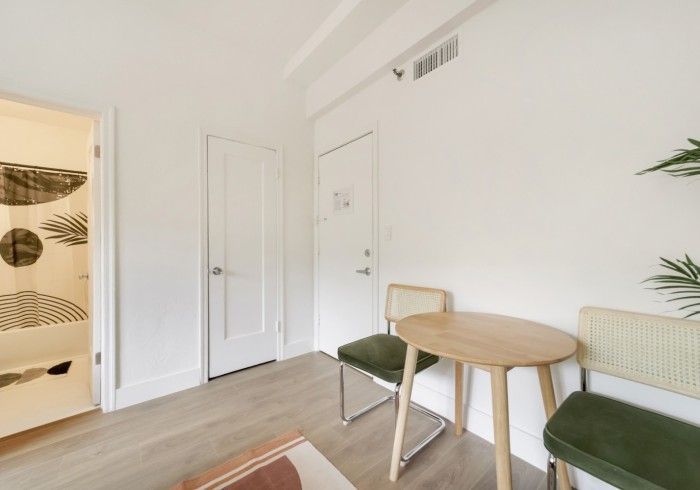 Minimal white room with a small round table, two chairs, and a patterned doorway curtain