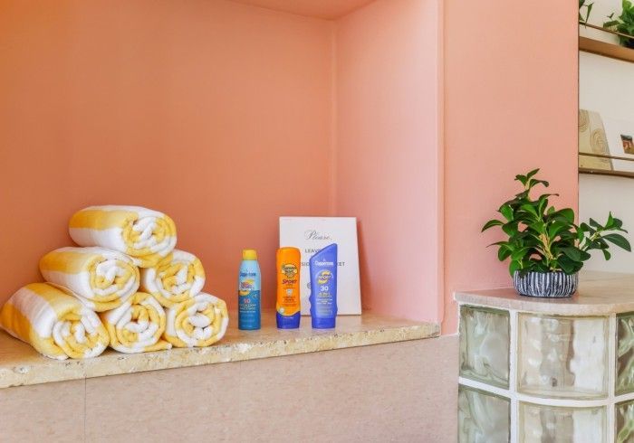 Spa countertop with rolled yellow towels, toiletries, and a potted plant against a peach wall