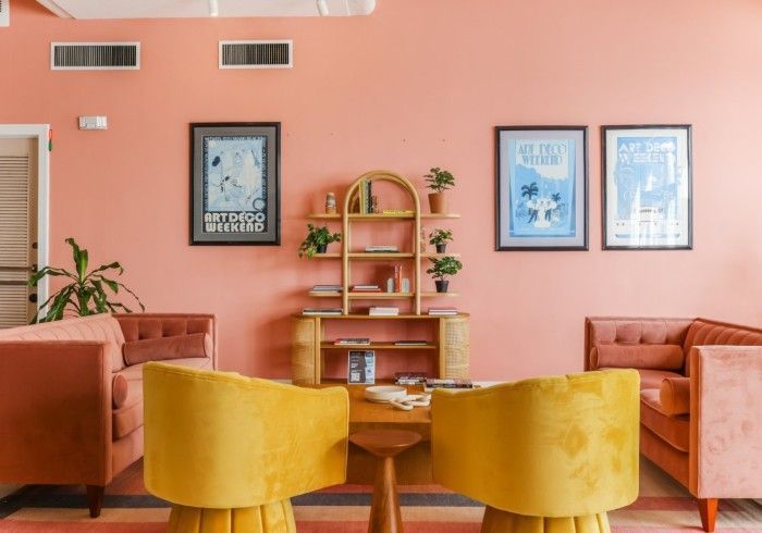 Cozy pink living room with mustard chairs, peach sofa, wall art, and a wooden shelf with plants