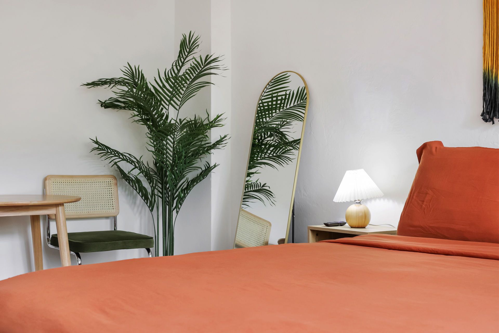 Cozy bedroom with orange bed, potted plant, chair, surfboard decor, and bedside lamp