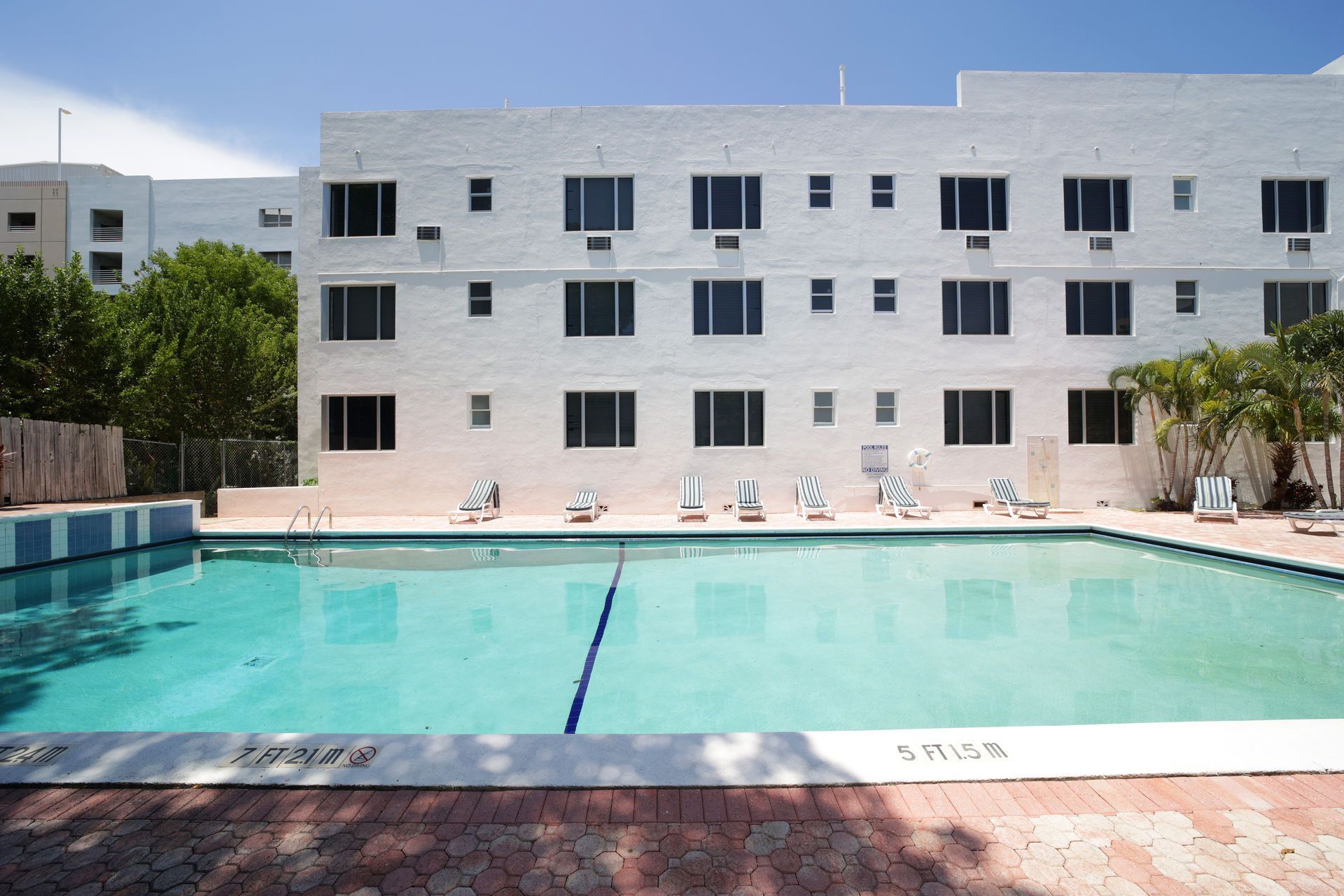 Outdoor swimming pool with turquoise water in front of a white apartment building