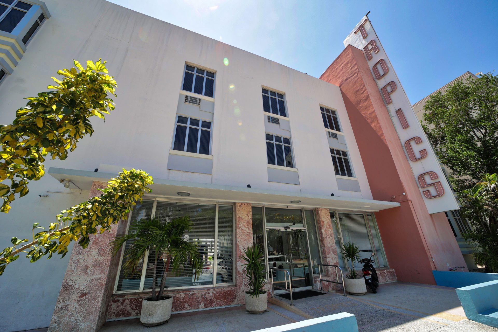 Modern white building with pink accent wall and vertical sign, viewed from below under a blue sky