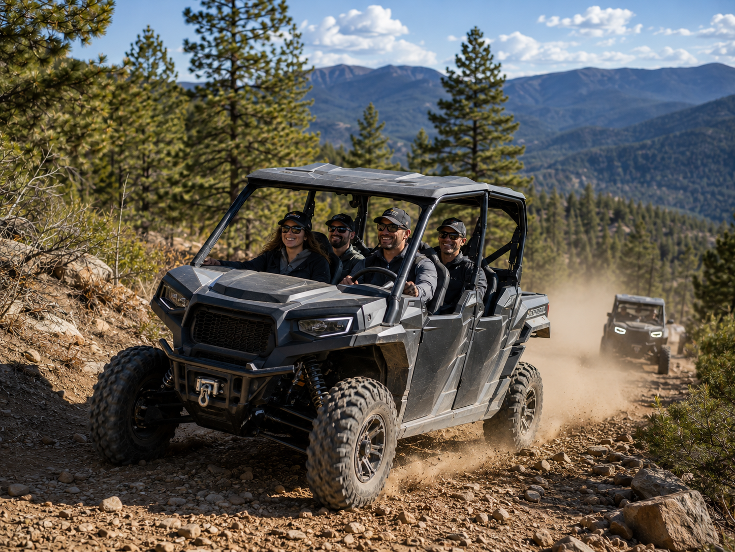 Two off-road UTVs drive on a dusty mountain trail with pine trees and distant peaks.