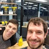 Two men are posing for a selfie in a gym.