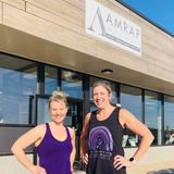 two women posing for a photo smiling outside of AMRAP Method gym