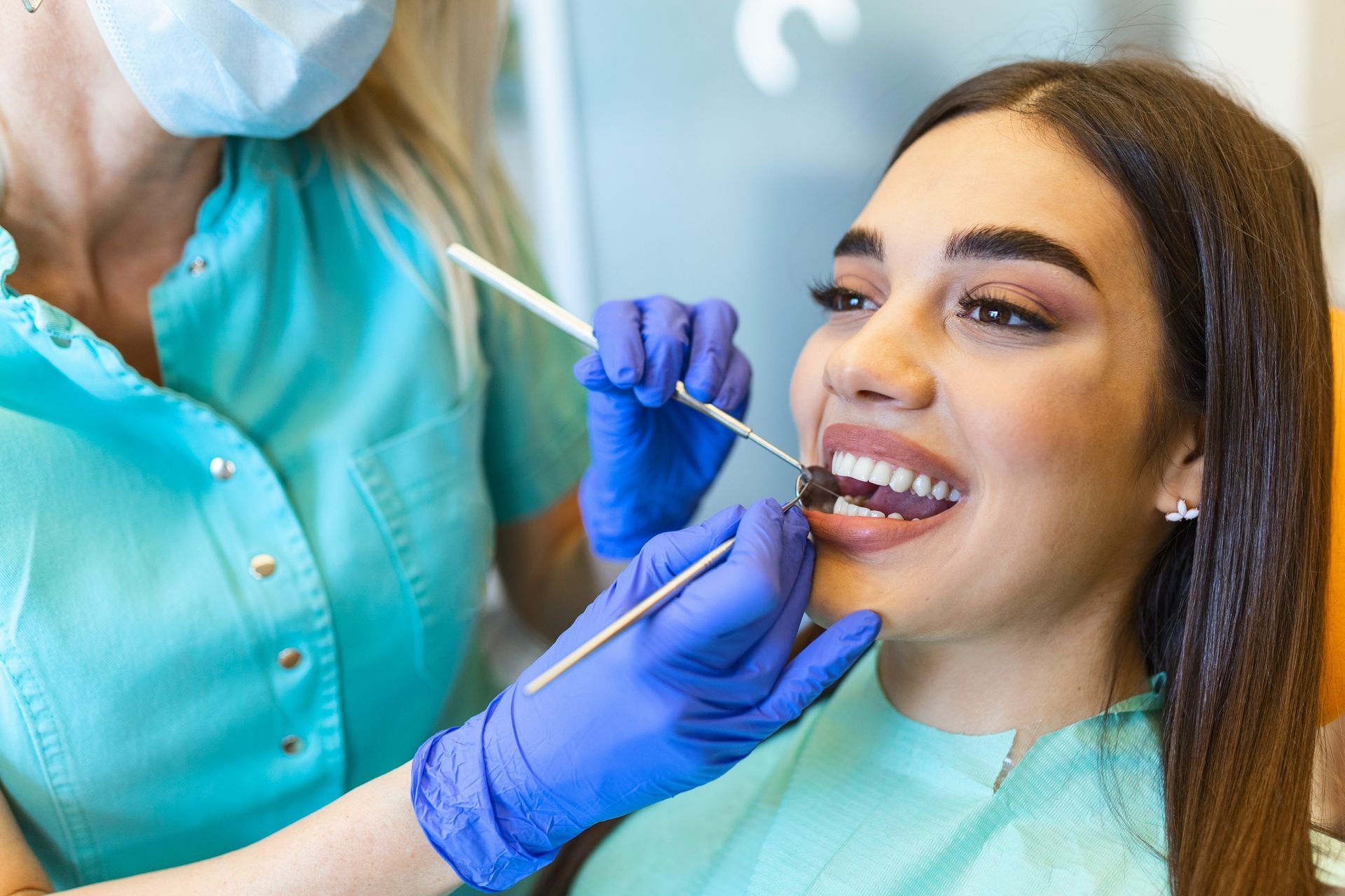 Young women smiling while Oral Hygienist examines her teeth.
