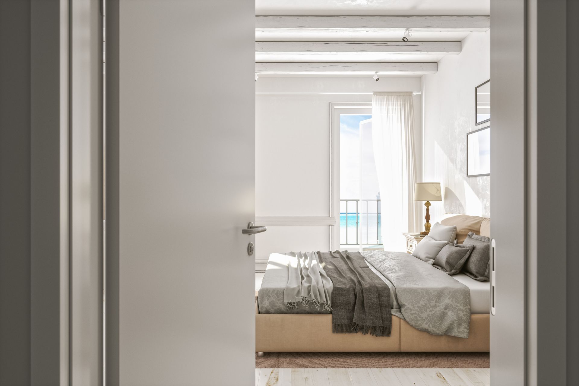 Interno della camera da letto, visto dalla porta; pareti bianche, letto con cuscini, finestra con vista sull'oceano.