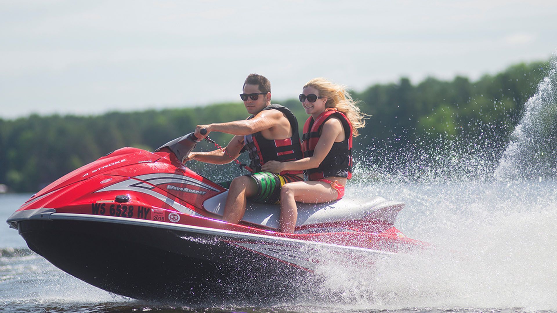 Couple riding a red jet ski on Lake Delton in Wisconsin Dells, creating a splash.