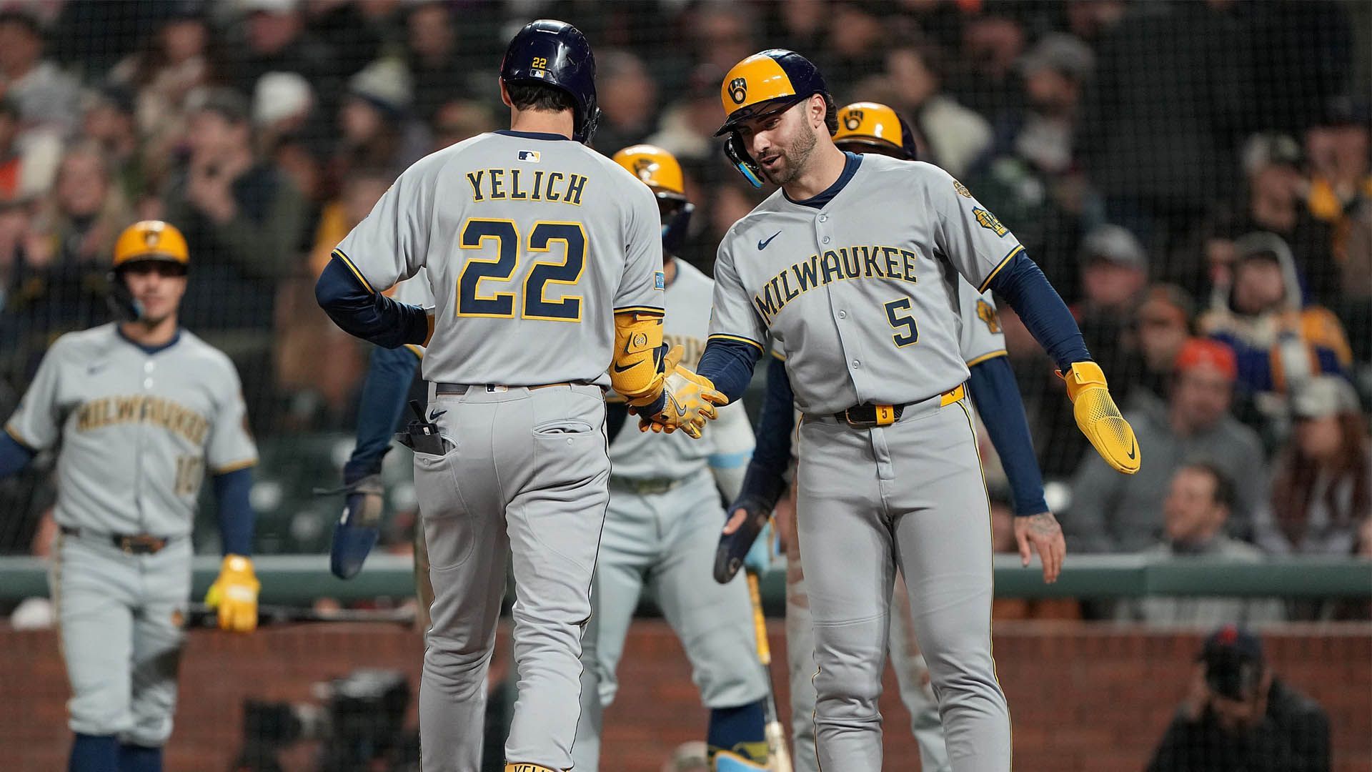 Milwaukee Brewers baseball players celebrating a run during a summer game.