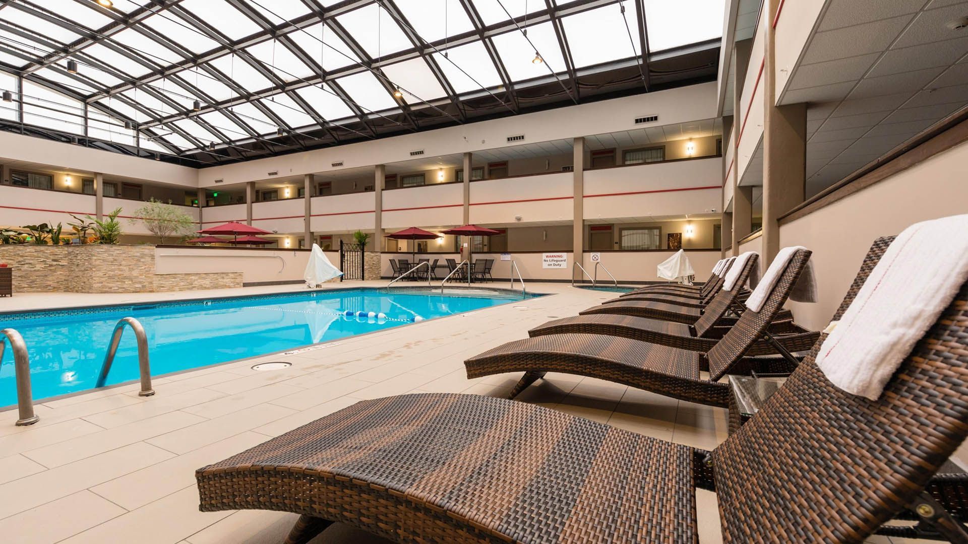 Indoor hotel swimming pool with lounge chairs and a glass roof in Milwaukee.