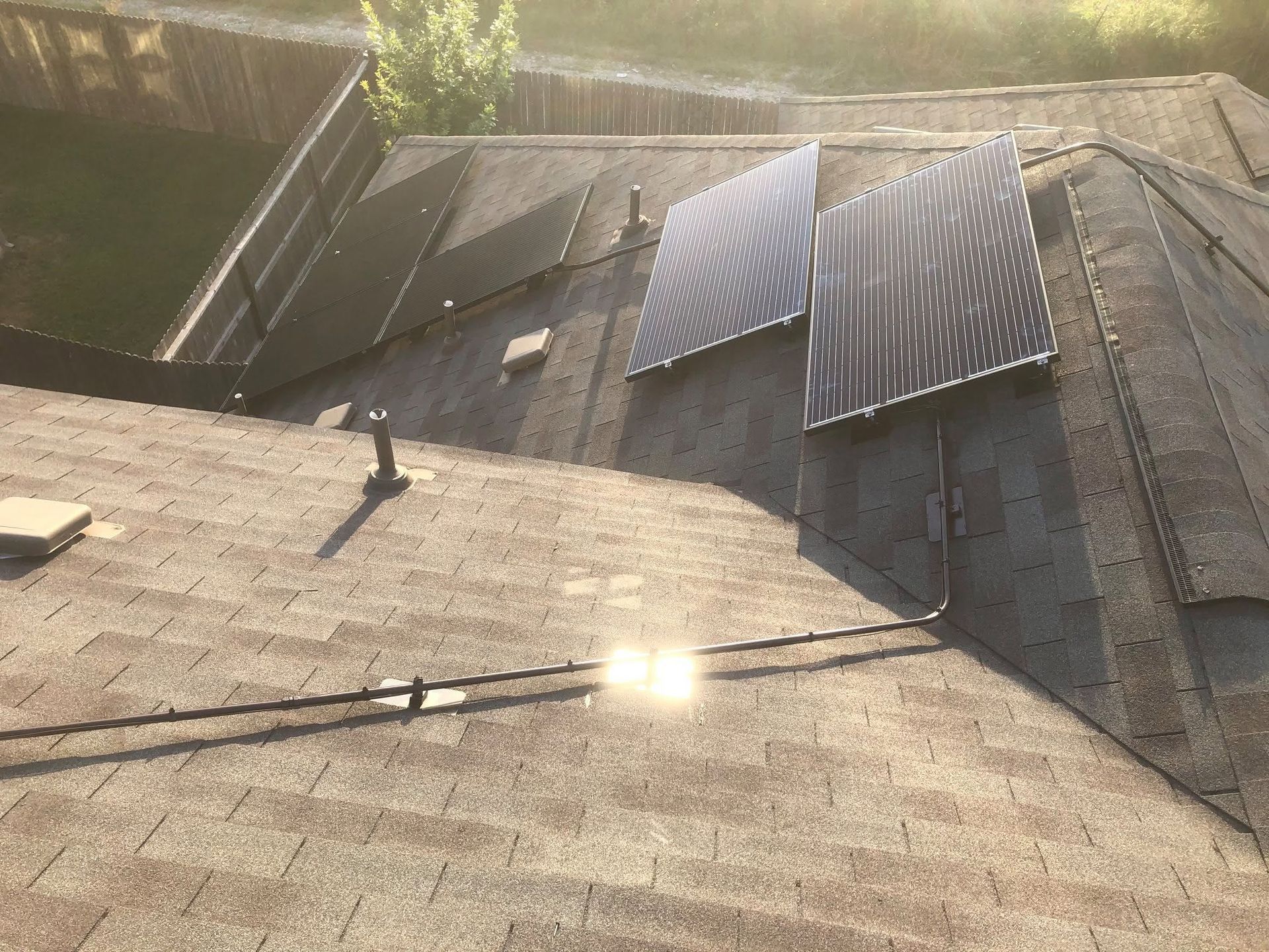Rooftop with several solar panels installed on shingles in warm sunlight