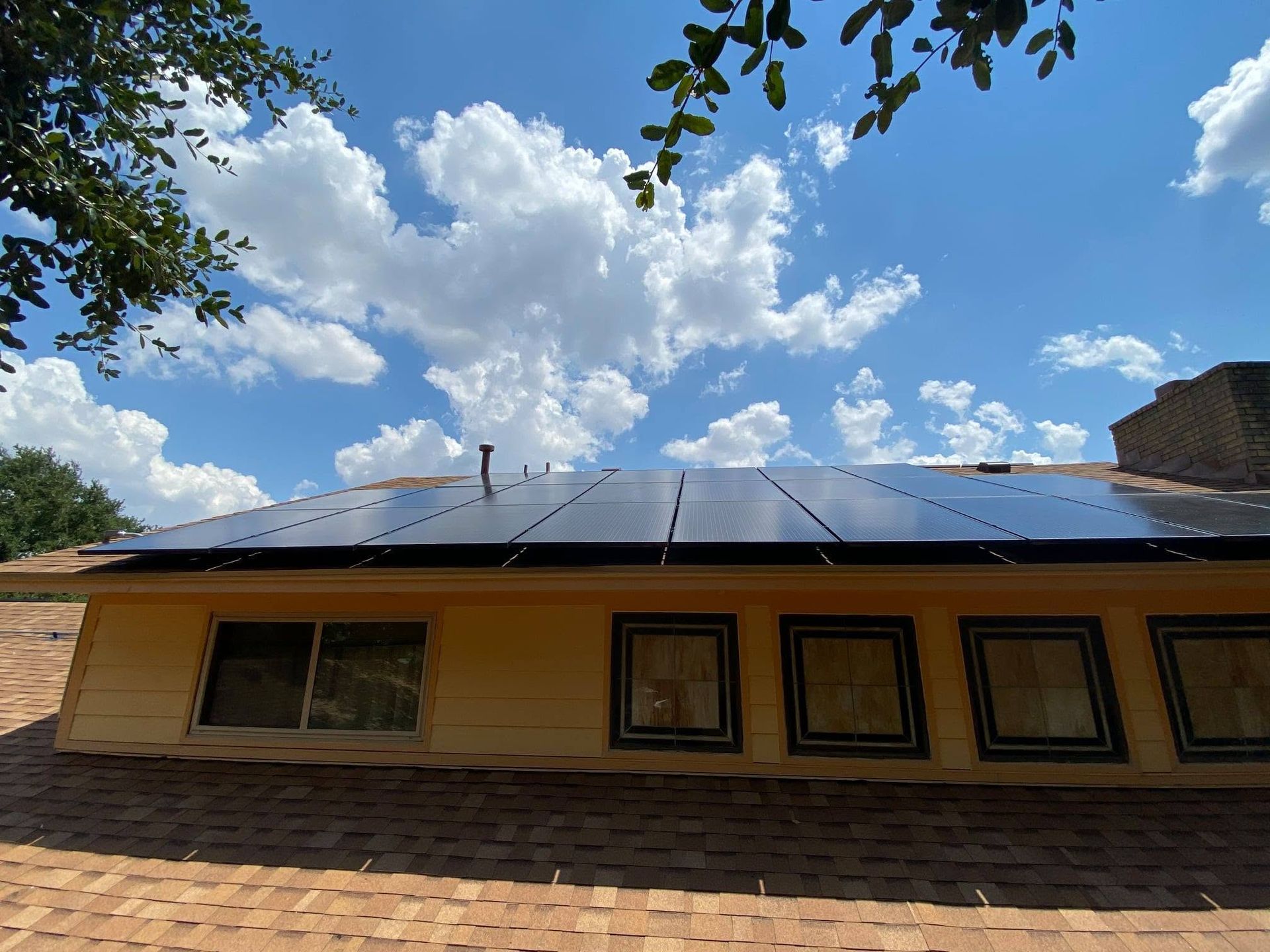 House roof with solar panels under a blue sky with clouds