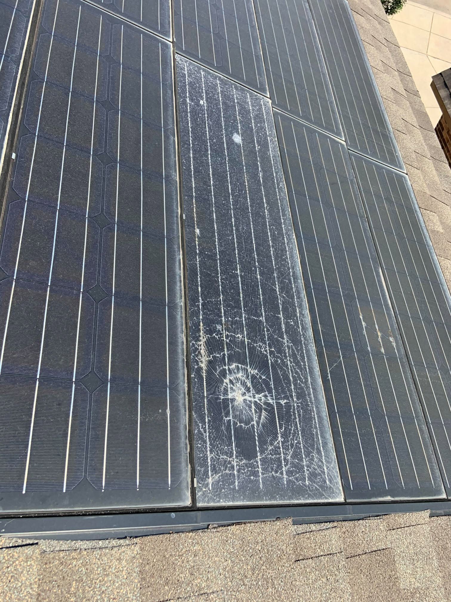 Close-up of a damaged solar panel with a cracked, weathered center section on a rooftop