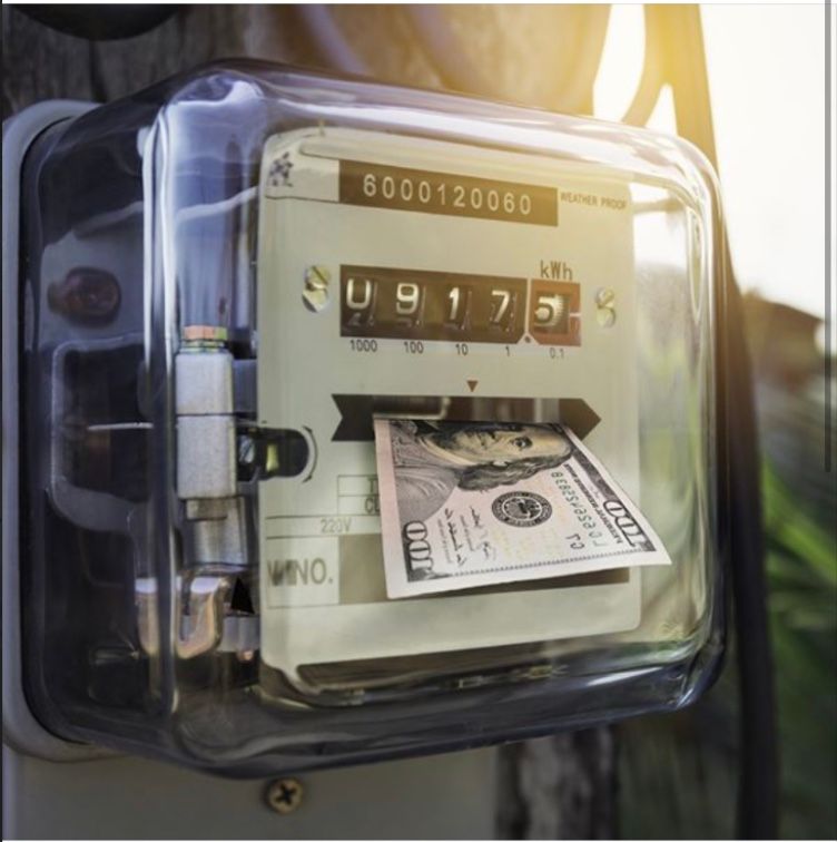 Close-up of a gas meter with a $100 bill tucked under the glass cover.