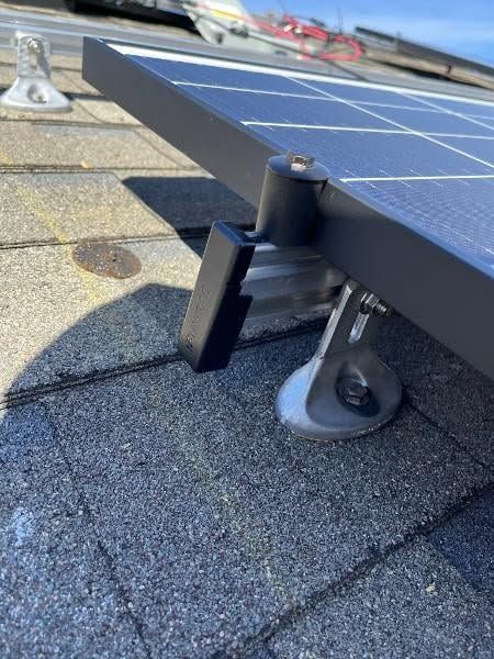 Solar panel mount on a shingled roof with a metal foot and support bracket.
