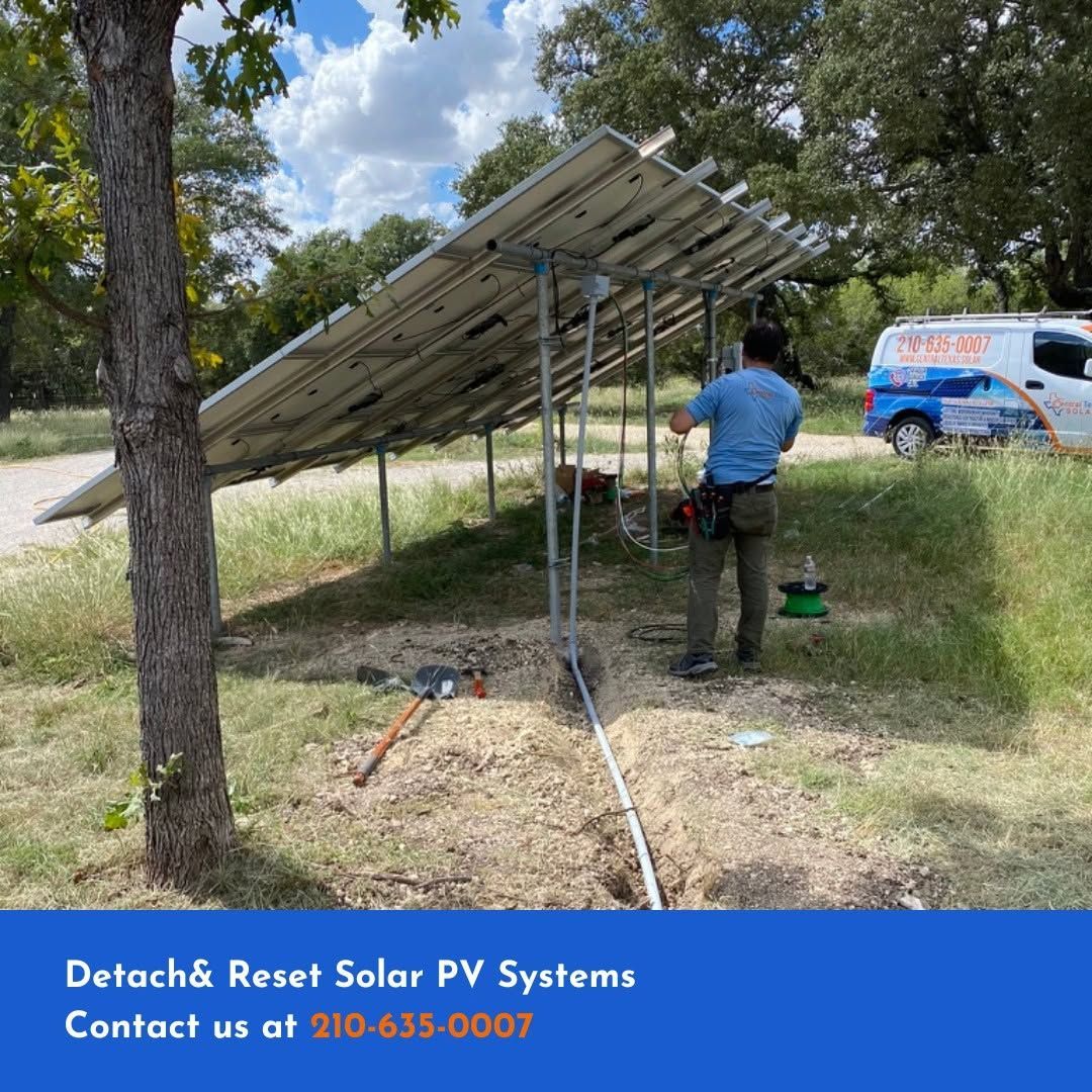 Worker resetting solar panels on a ground mount beside a van in a grassy yard