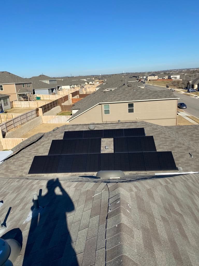 Rooftop with solar panels and a shadow of the photographer under a clear blue sky.