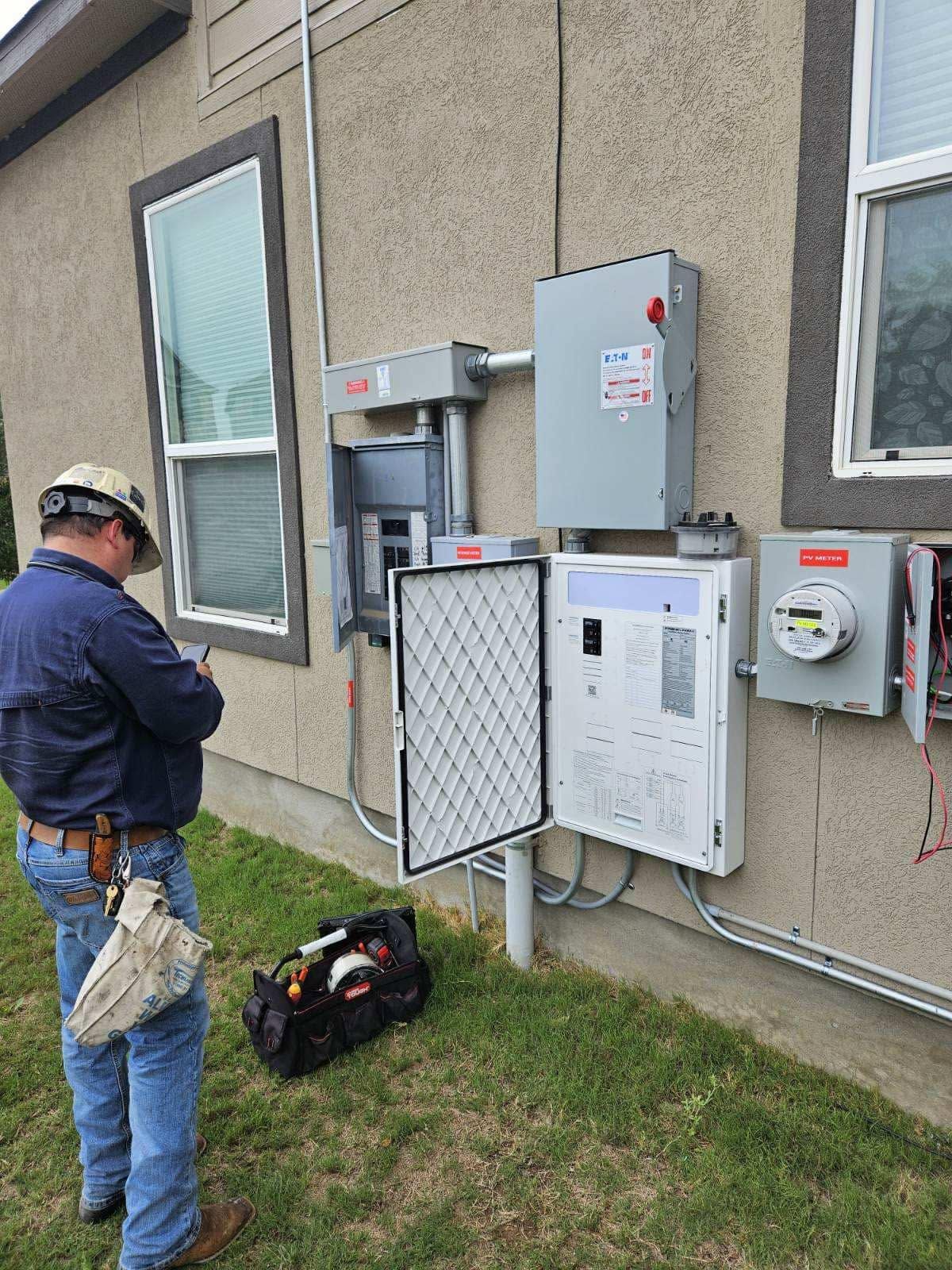Worker inspecting outdoor electrical utility boxes on a building wall