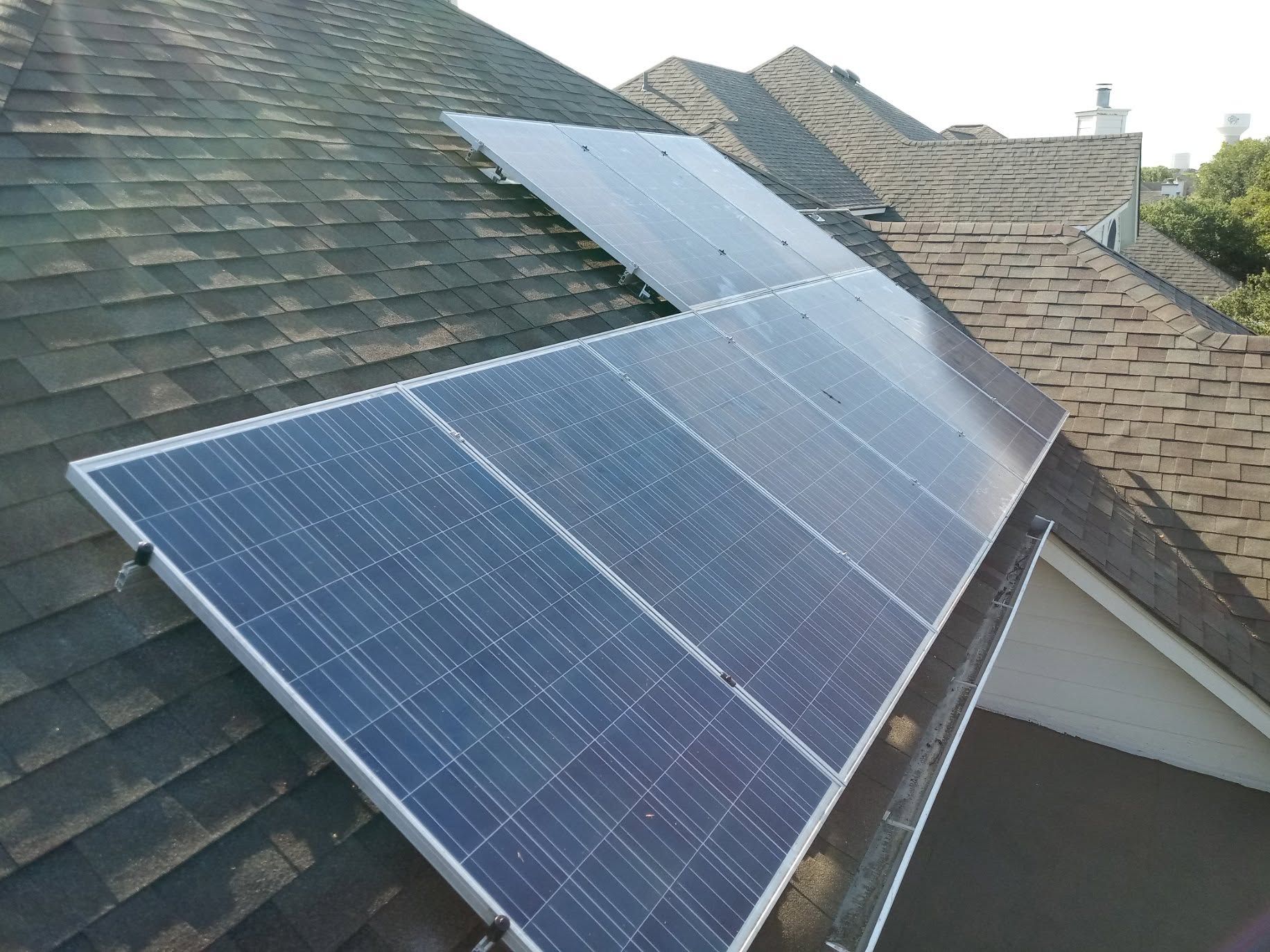 Solar panels installed on a sloped shingled roof, with a blue panel near the foreground.